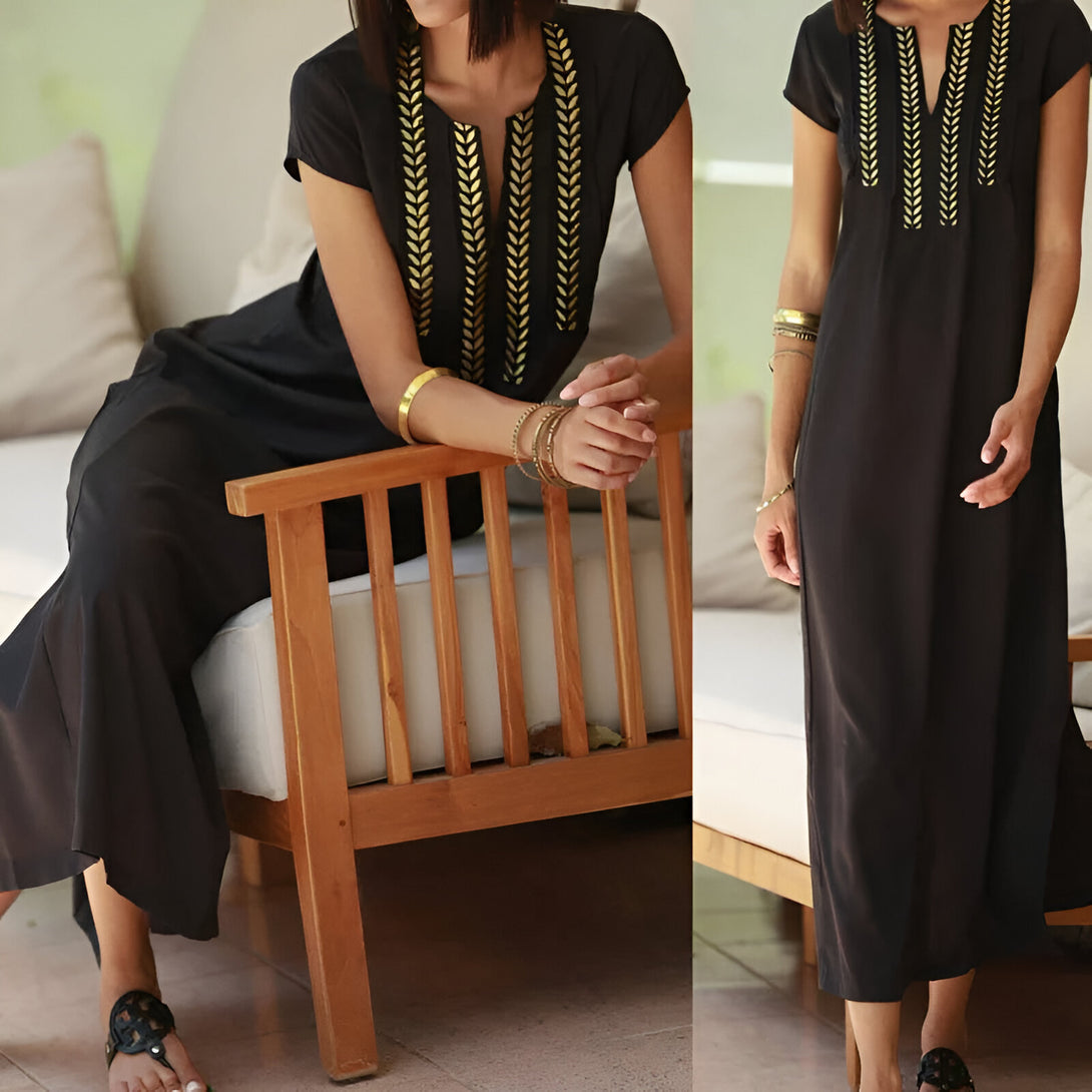 Une femme porte une robe noire à manches courtes avec des broderies dorées. La robe est élégante et confortable, idéale pour les occasions spéciales ou le quotidien.