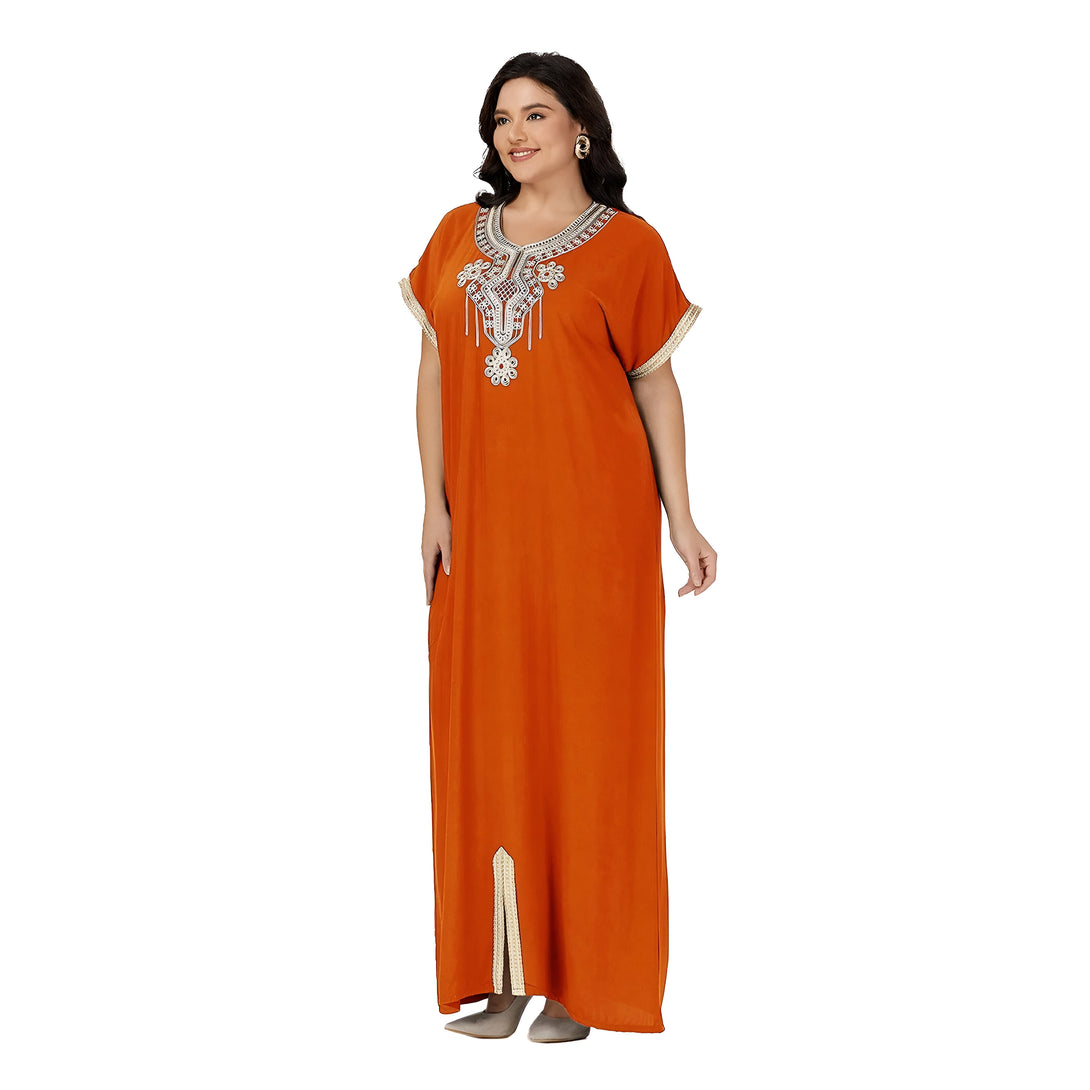 Une femme porte une robe longue orange avec des broderies dorées. La robe a des manches courtes et une fente sur le devant.