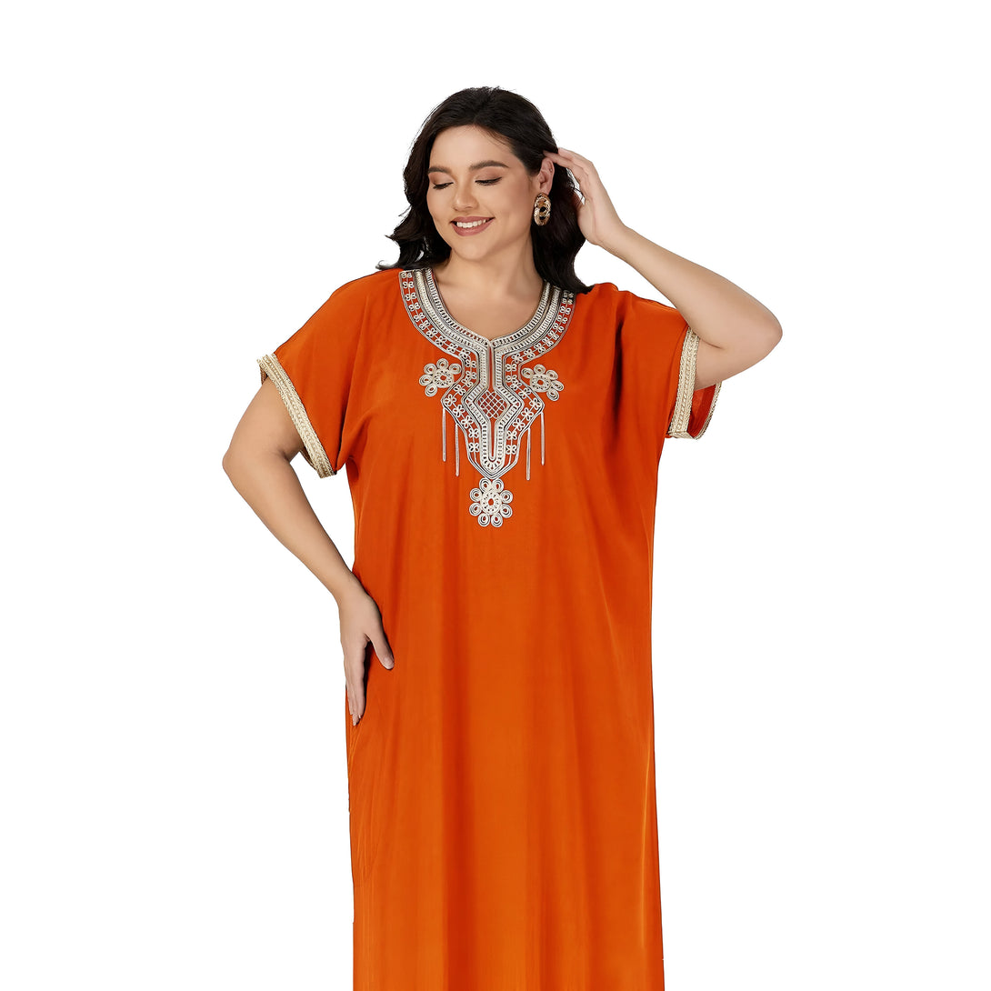 Une femme portant une robe orange à manches courtes avec une broderie dorée. La robe est ample et flottante, idéale pour les occasions spéciales ou décontractées.