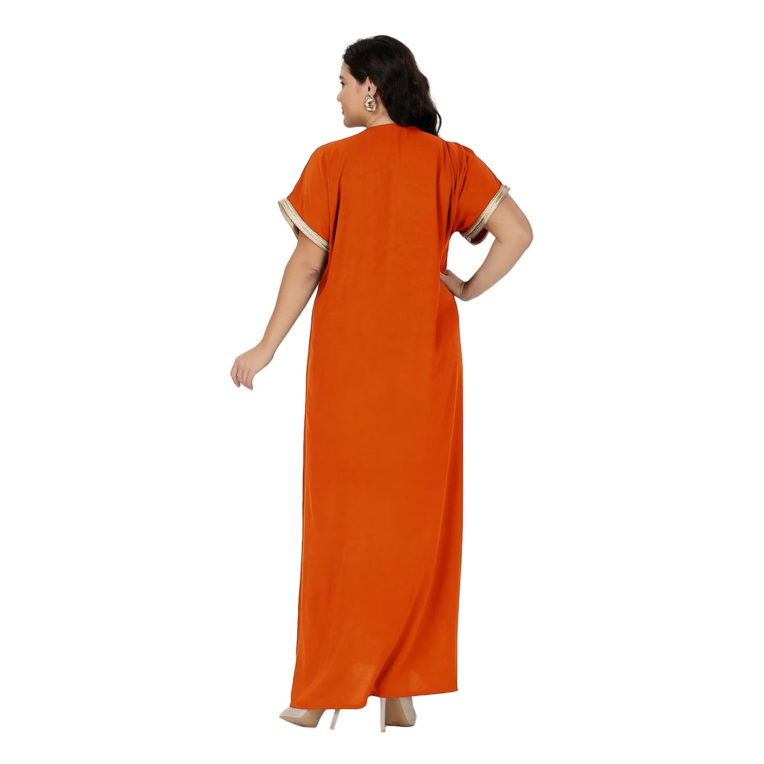Une femme porte une longue robe orange avec des manches courtes et des détails dorés. La robe est ample et fluide, idéale pour les occasions spéciales.