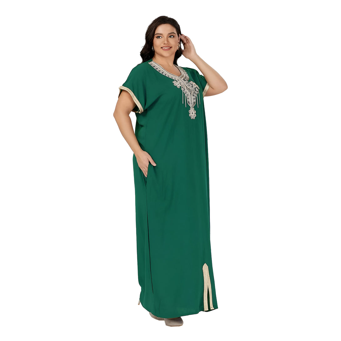 Une femme portant une robe verte à manches courtes avec des broderies dorées. La robe est ample et a une fente sur le côté.