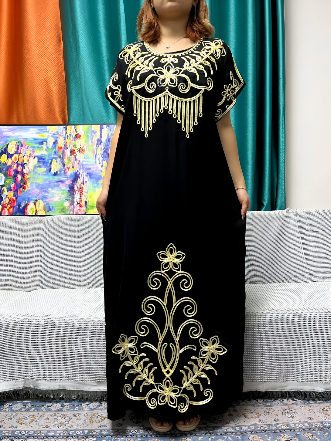 Robe noire longue avec des détails brodés dorés, parfaite pour les occasions spéciales.  La robe est ornée de motifs floraux et de fils dorés qui ajoutent une touche d'élégance.