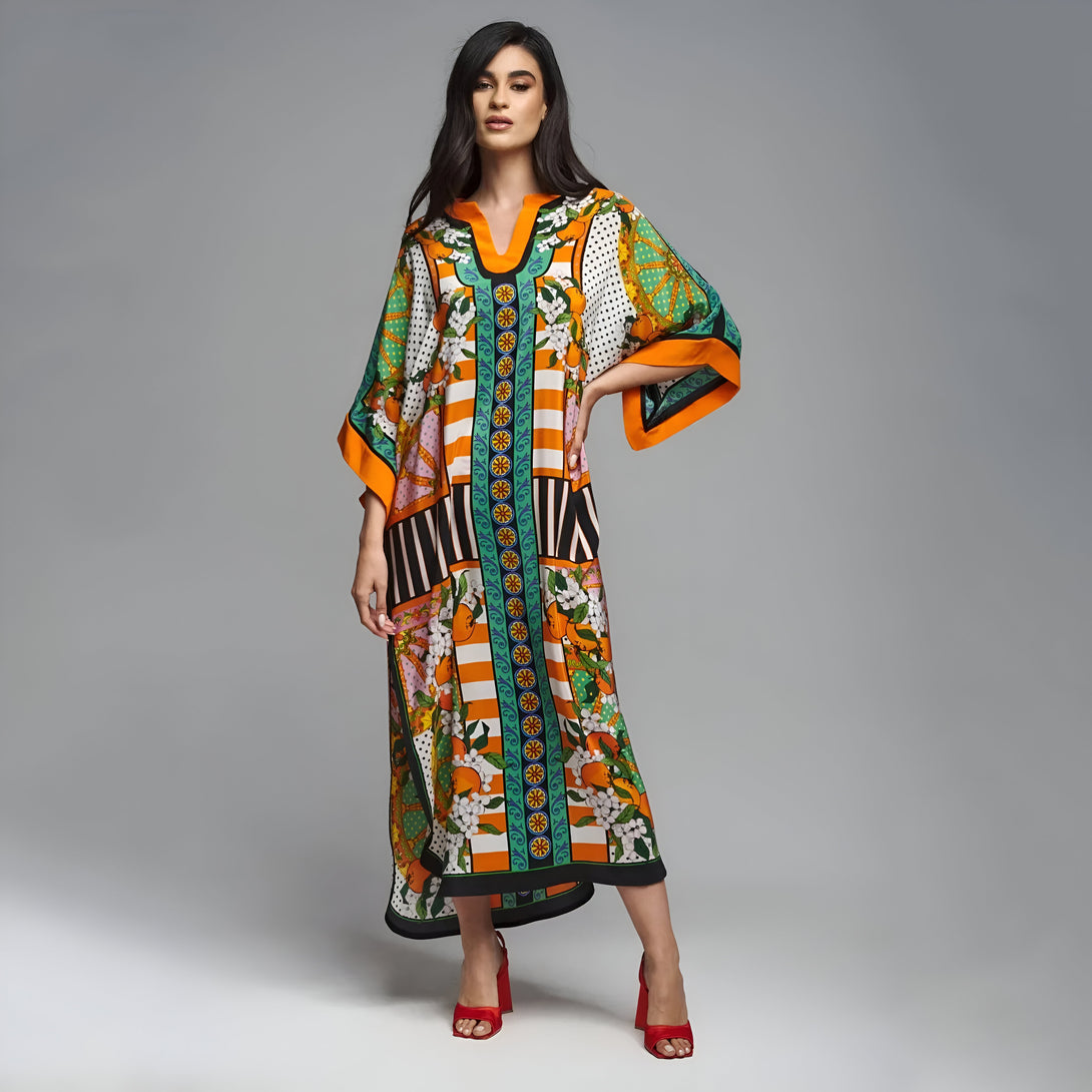 Une femme porte une robe longue musulmane orange et verte à motifs floraux et géométriques.