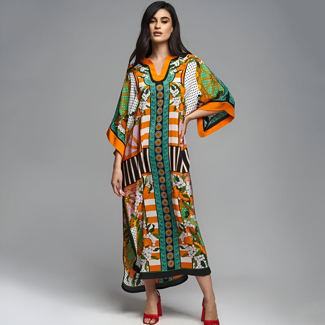 Une femme porte une longue robe musulmane orange, verte et noire à imprimé floral. La robe a des manches amples et une coupe ample. Elle porte des chaussures à talons rouges.