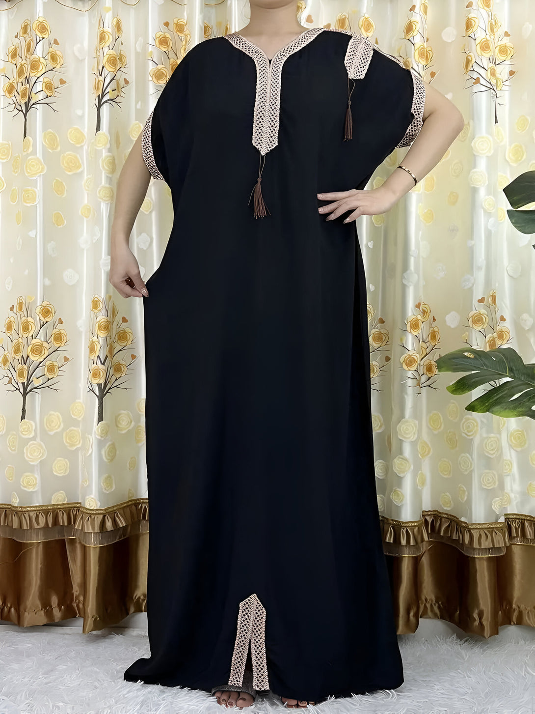 Une robe noire ample avec des détails en dentelle beige, idéale pour les femmes musulmanes. La robe a une encolure en V et des manches courtes.