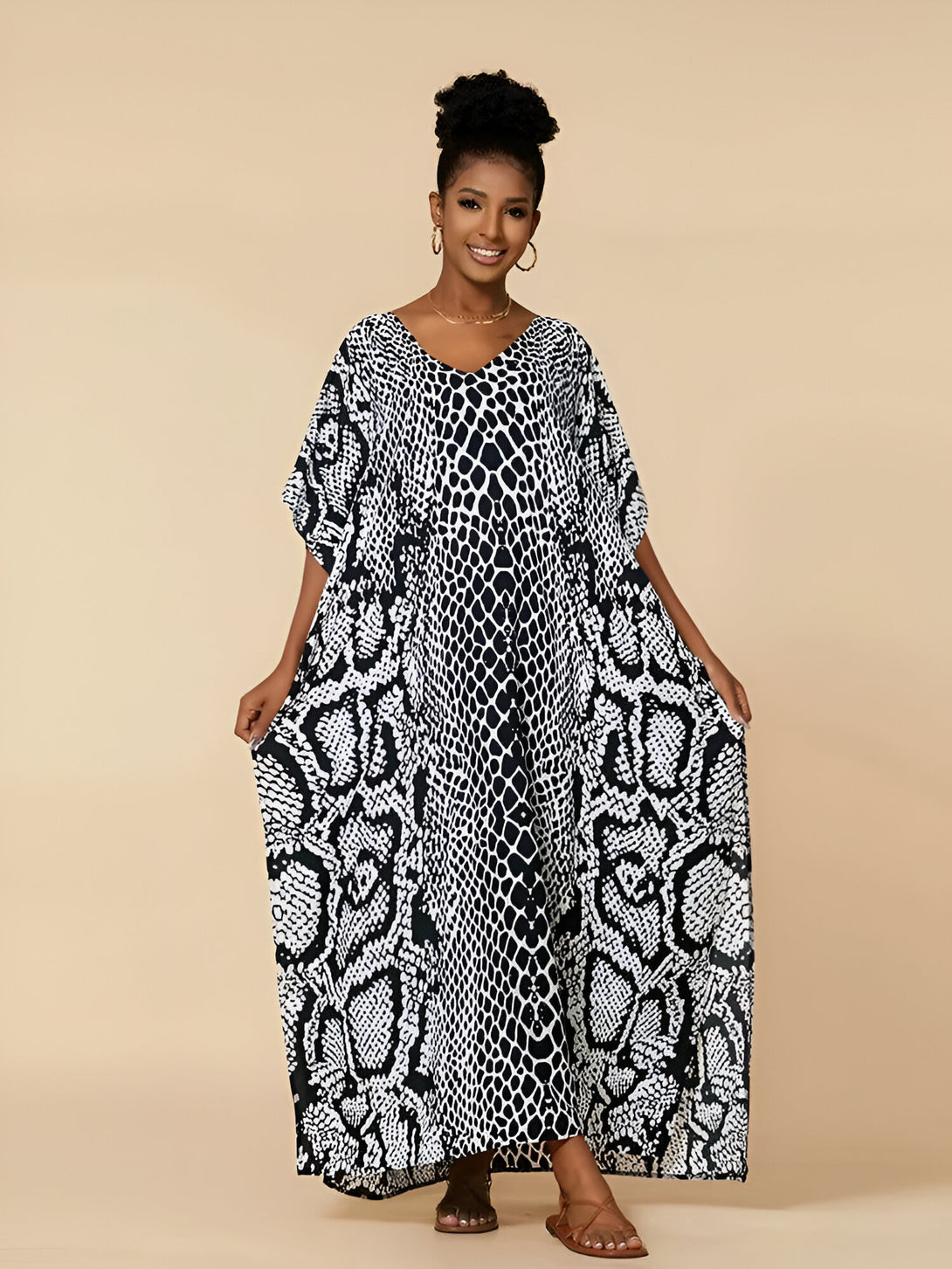 Une femme porte une longue robe noire et blanche à imprimé serpent. La robe est ample et a des manches courtes. La robe est parfaite pour les occasions spéciales ou pour tous les jours.