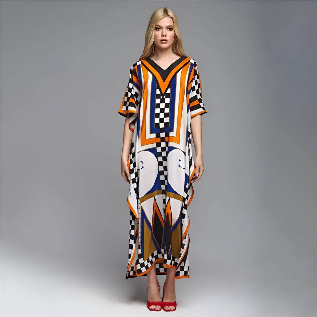 Une femme portant une robe longue de style musulman avec un imprimé géométrique en orange, bleu et noir sur fond blanc.  La robe a un col en V et des manches courtes.  La femme porte des talons rouges.