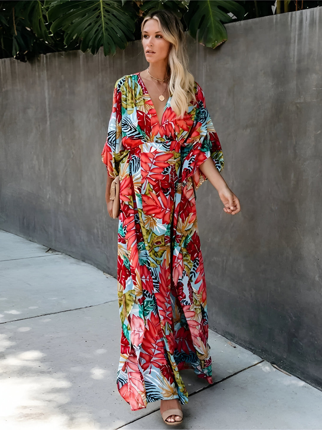 Une femme porte une longue robe à manches 3/4 avec un imprimé floral coloré. La robe est parfaite pour les occasions décontractées et les sorties estivales.