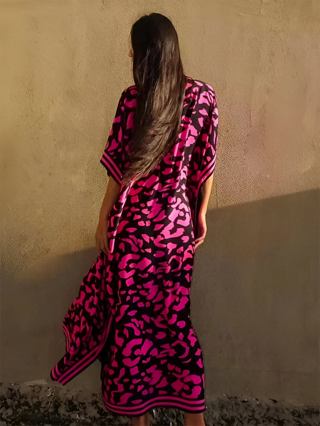 Une femme porte une longue robe rose à imprimé léopard. La robe est ample et fluide, idéale pour les jours chauds.