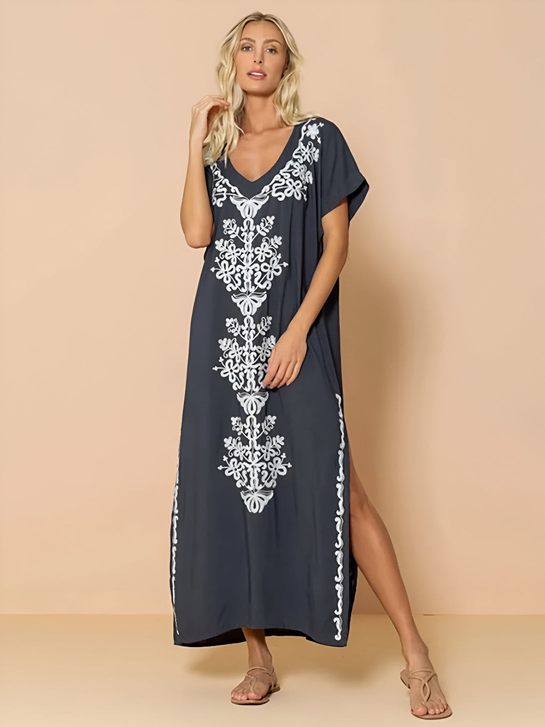 Une robe longue bleu foncé avec une broderie blanche sur le devant. La robe a un col en V et des manches courtes.  La robe a deux fentes sur les côtés. La robe est parfaite pour les occasions spéciales ou pour une tenue décontractée.