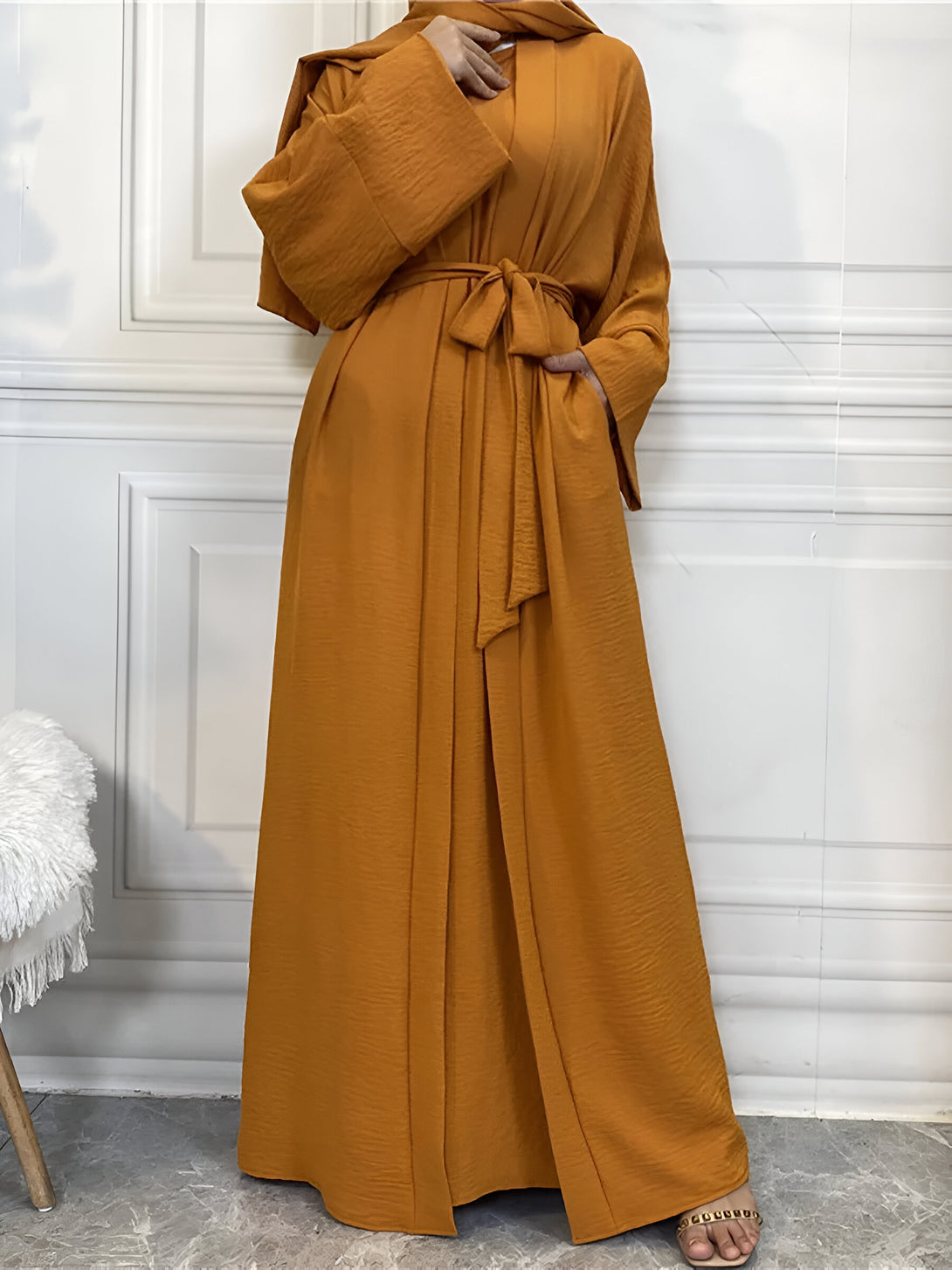 Une robe abaya musulmane longue et élégante de couleur moutarde avec une ceinture à nouer. Elle est parfaite pour les occasions spéciales ou pour un usage quotidien.