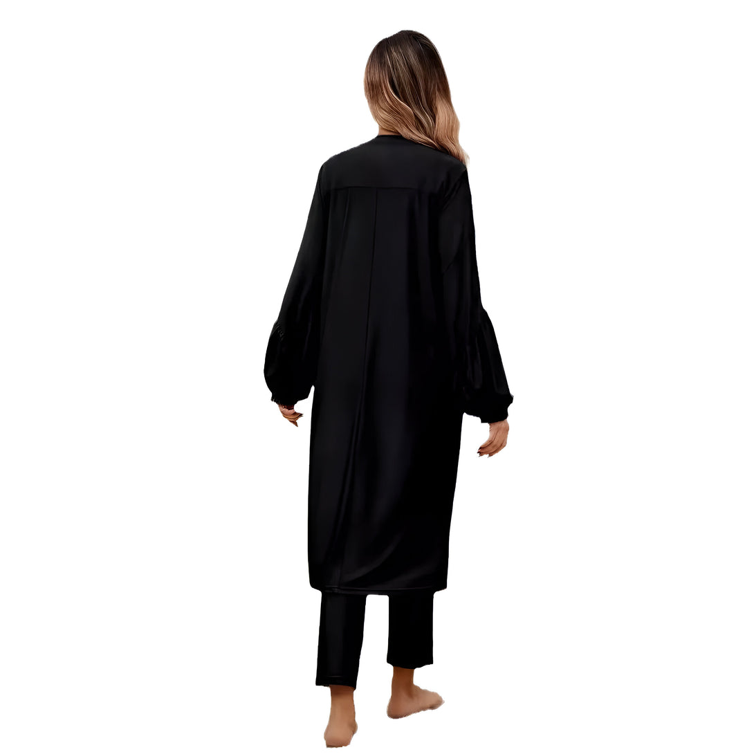 Une femme portant une robe noire longue et ample avec des manches bouffantes. Elle porte également un pantalon noir.  La robe est élégante et confortable, parfaite pour les occasions spéciales ou pour un look décontracté.