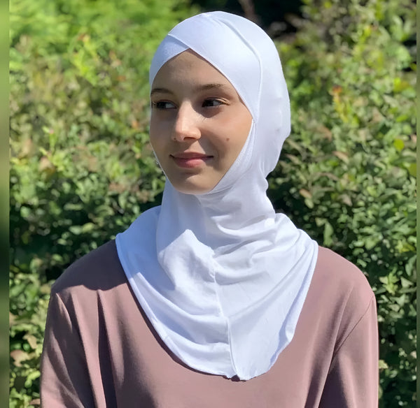 Une femme portant un hijab blanc en tissu extensible, parfait pour un look élégant et confortable.