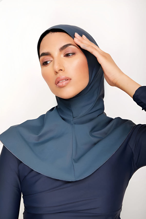 Une femme porte un hijab de bain bleu foncé et un maillot de bain assorti.  Le hijab est conçu pour couvrir les cheveux et le cou pendant la natation.  Le maillot de bain est élégant et modeste, parfait pour la baignade à la plage ou à la piscine.