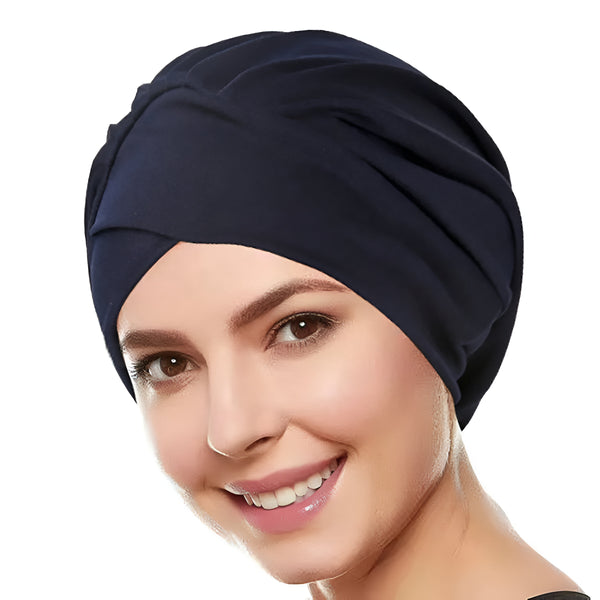 Une femme souriante portant un turban bleu foncé en tissu.