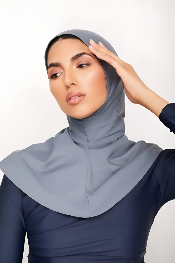 Une femme portant un hijab gris et un maillot de bain musulman bleu marine.