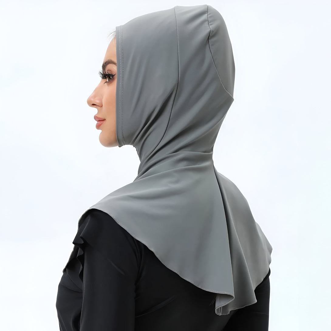 Une femme portant un hijab gris foncé en tissu extensible, parfait pour un look élégant et confortable.