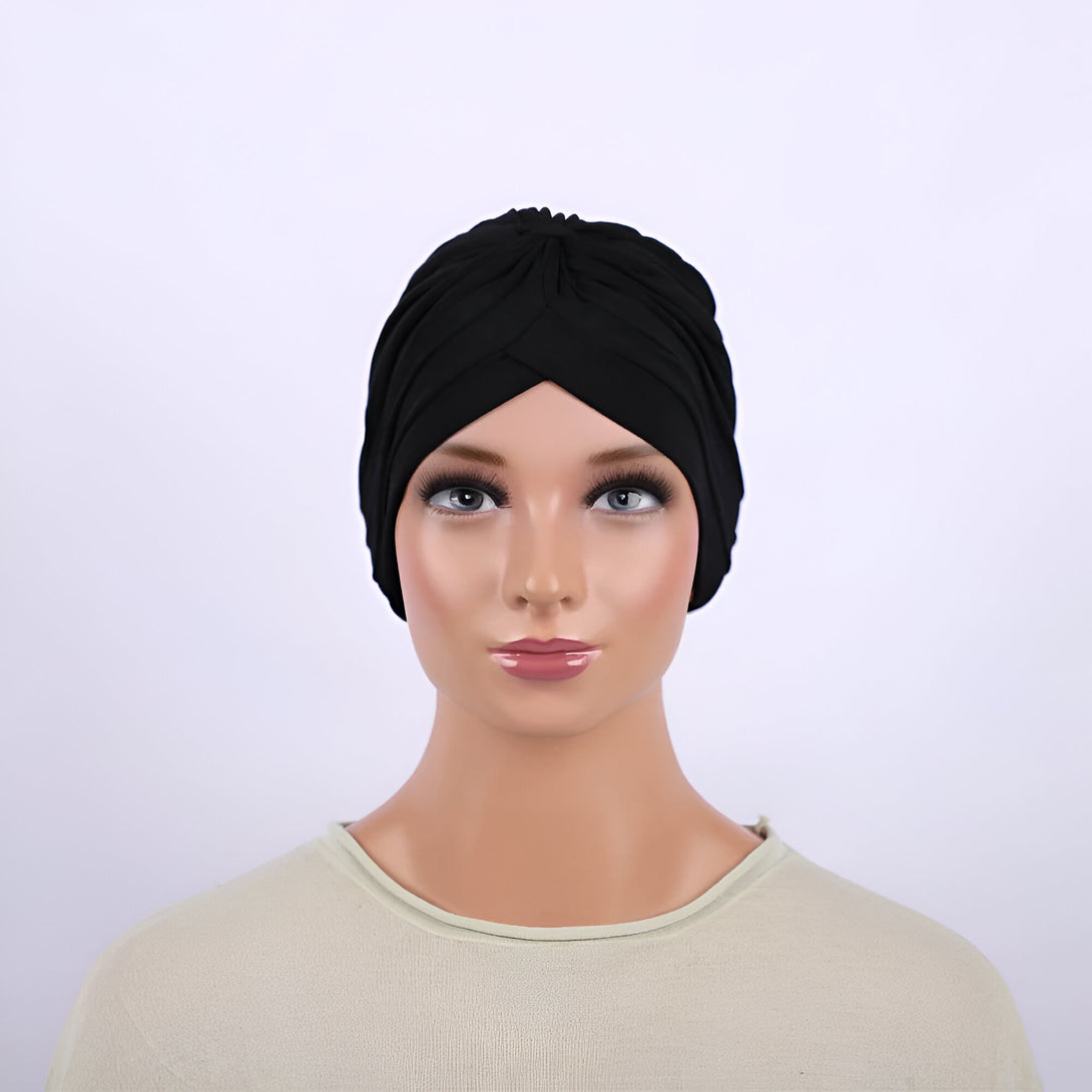 Un mannequin portant un turban noir en tissu extensible. Le turban est élégant et facile à porter.