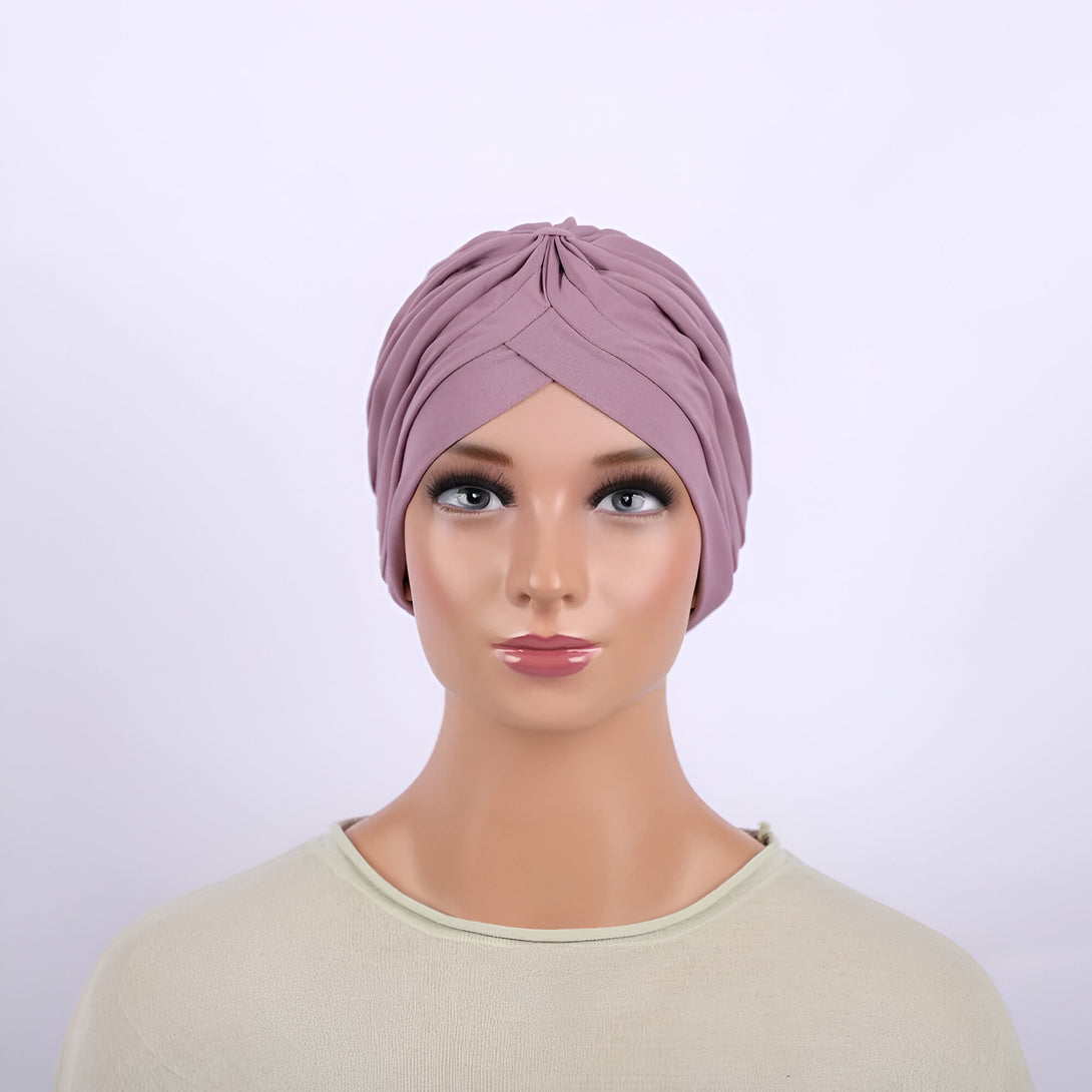 Un mannequin portant un turban mauve élégant et chic, parfait pour les femmes musulmanes qui souhaitent un look à la fois moderne et modeste.