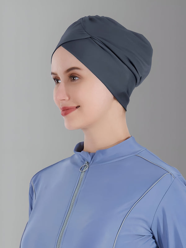 Une femme souriante porte un hijab gris foncé et une tenue de sport bleue.