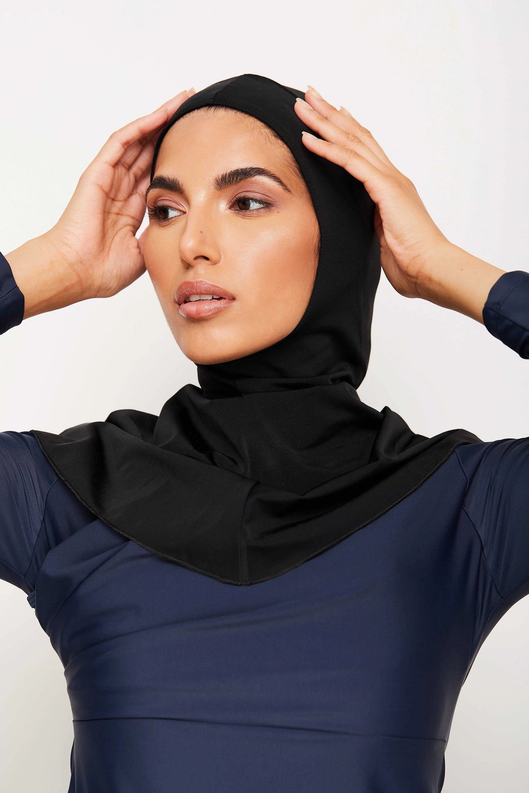 Une femme portant un hijab noir et une robe bleu marine.  Elle porte un vêtement musulman élégant et moderne.