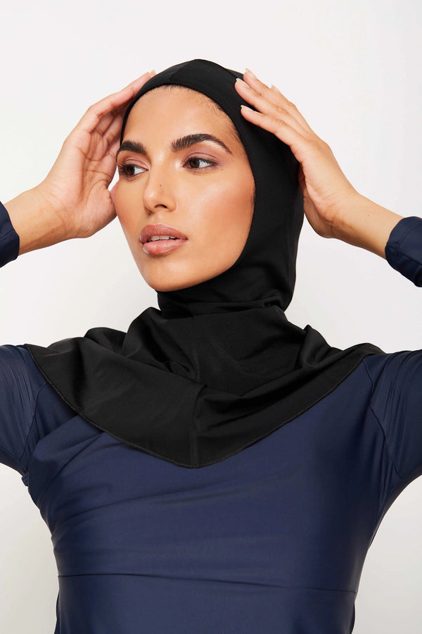 Une femme portant un hijab noir et une robe bleu marine.  Elle porte un vêtement musulman élégant et moderne.