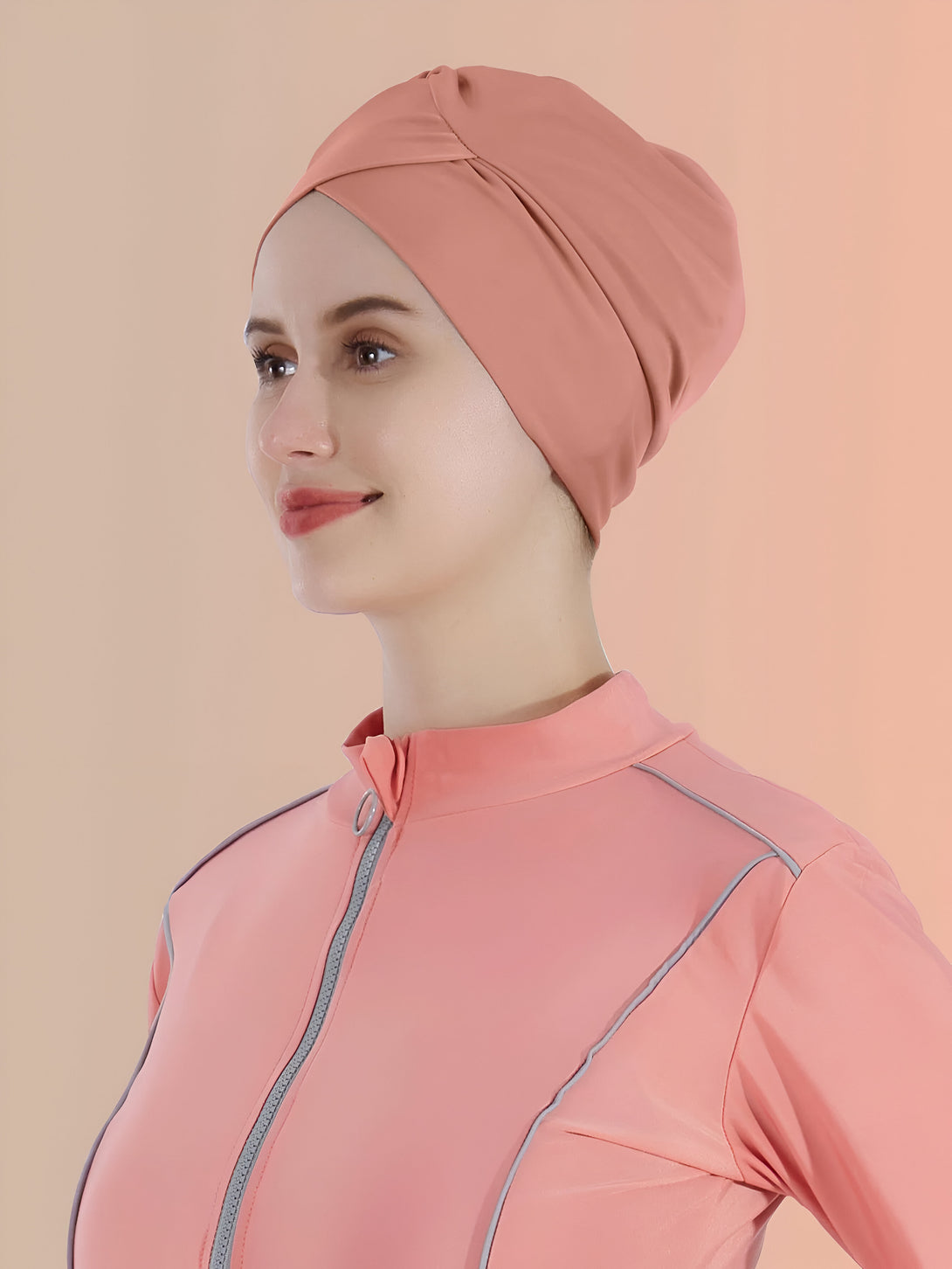 Une femme portant un hijab rose et un maillot de bain musulman rose avec des détails gris.  Vêtements modestes et chics pour la natation.