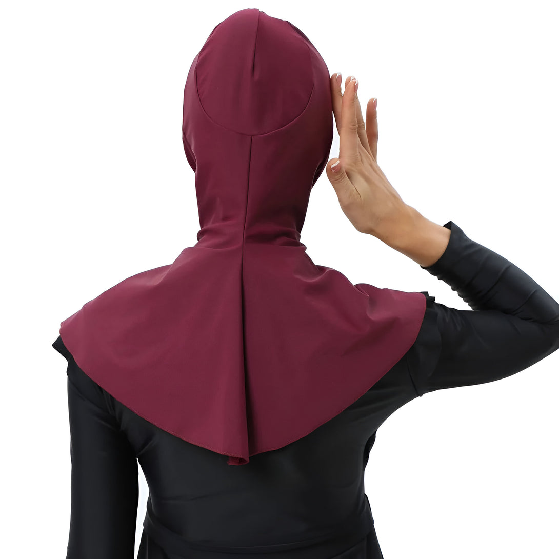 Une femme porte un hijab de bain bordeaux. Le hijab est conçu pour couvrir les cheveux et le cou pendant la baignade.