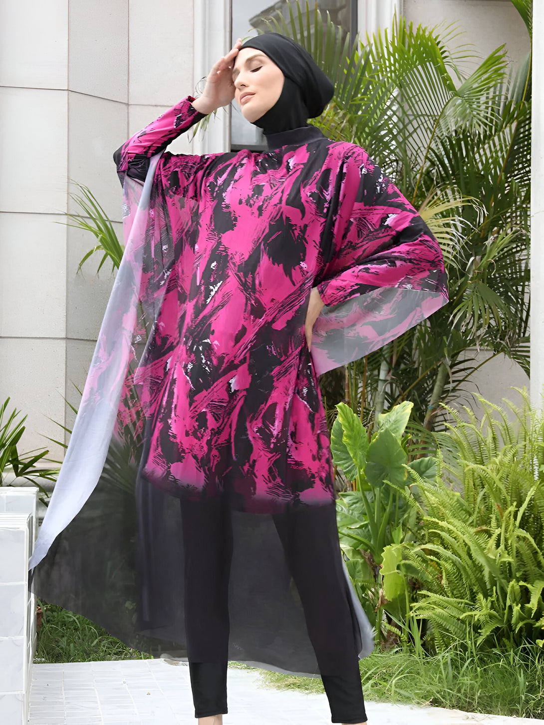Une femme portant un maillot de bain musulman rose et noir avec un hijab noir.