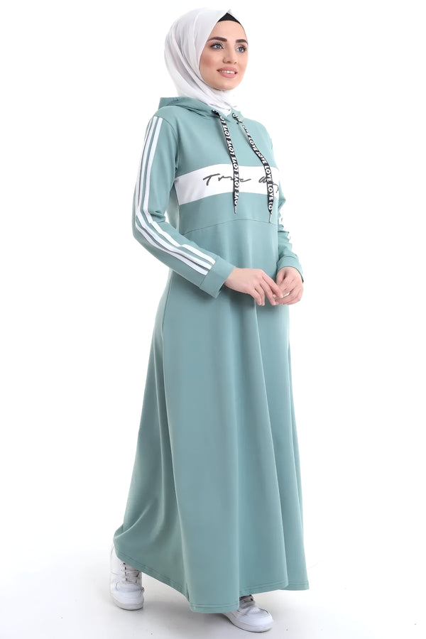 Une femme portant une robe à capuche bleu sarcelle avec des rayures blanches et un imprimé "Love" sur la capuche. La robe a une coupe ample et est parfaite pour un look décontracté et tendance.