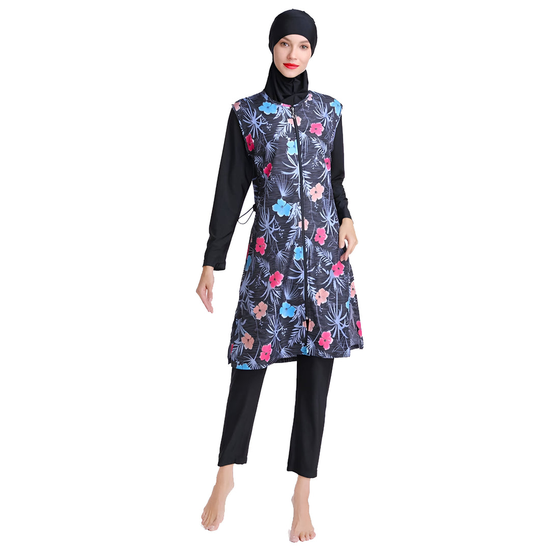 Une femme portant un maillot de bain musulman noir à fleurs. La combinaison est munie d'une fermeture éclair sur le devant et de manches longues. La femme porte un hijab noir.