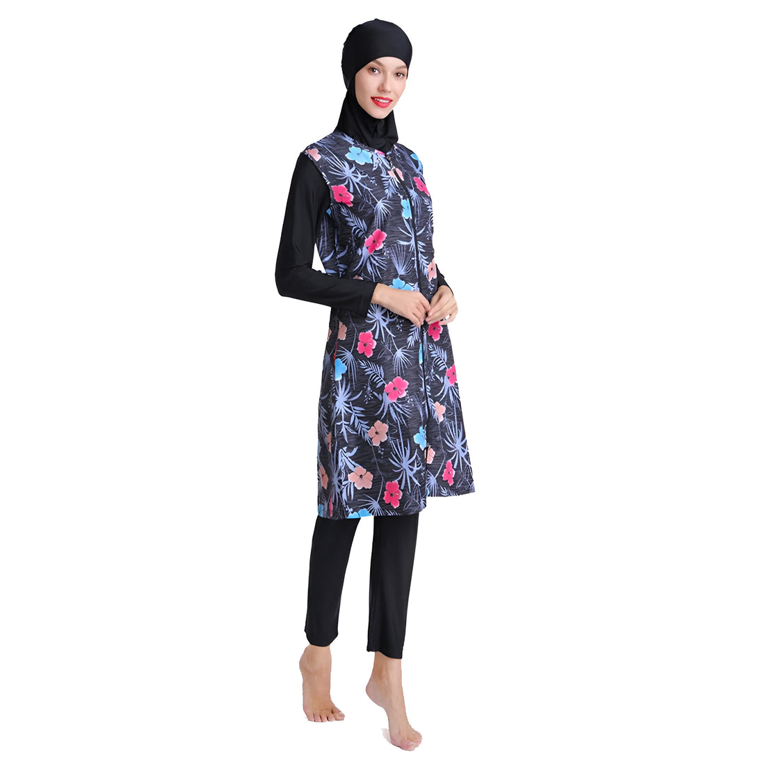 Une femme portant un maillot de bain musulman noir à fleurs. Le maillot de bain comprend une longue tunique avec des manches longues et un pantalon long. La femme porte également un hijab noir.