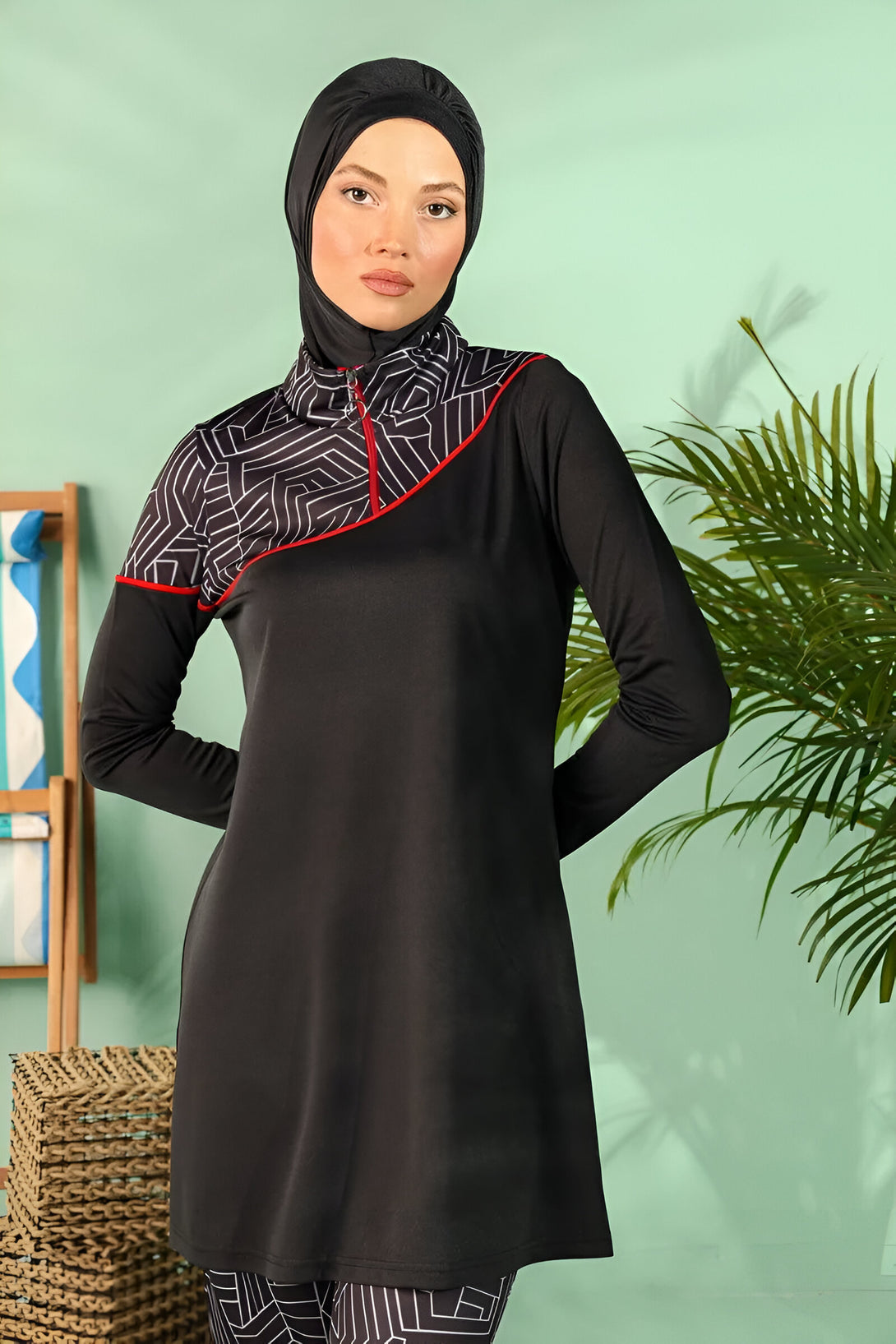 Une femme portant un hijab noir et une tenue de bain musulmane noire avec des détails géométriques blancs.