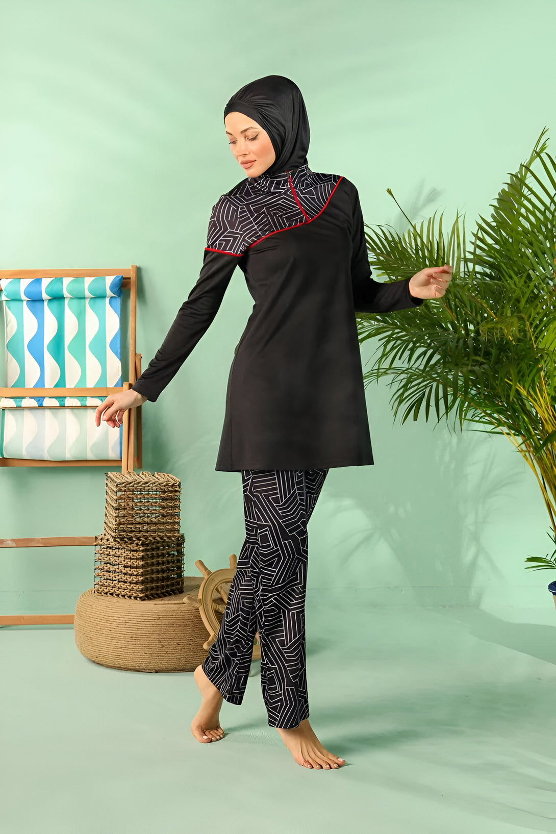 Une femme portant un maillot de bain musulman noir avec des motifs géométriques blancs. Le maillot de bain comprend une tunique à manches longues et un pantalon long.  La femme porte un hijab noir.