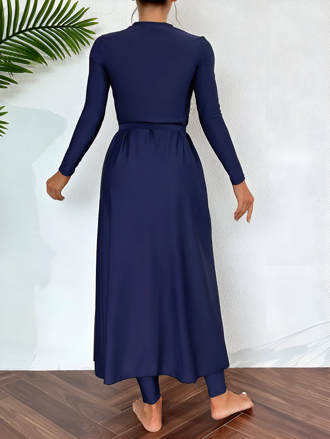 Une femme portant une longue robe bleue marine à manches longues, idéale pour la natation ou la plage. La robe est élégante et confortable.