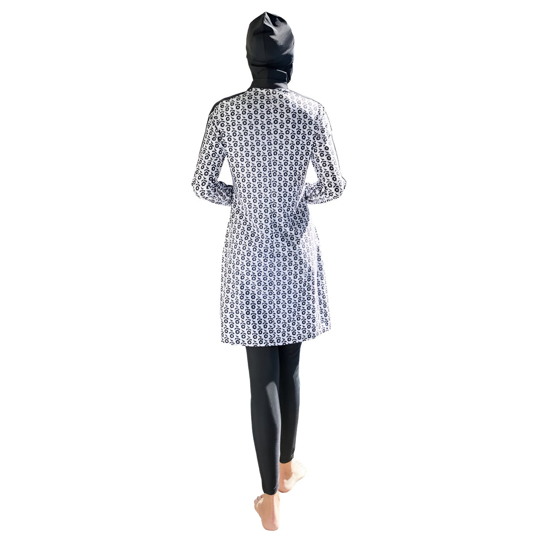 Une femme portant un maillot de bain musulman noir et blanc à motifs floraux. Elle porte un hijab noir assorti.