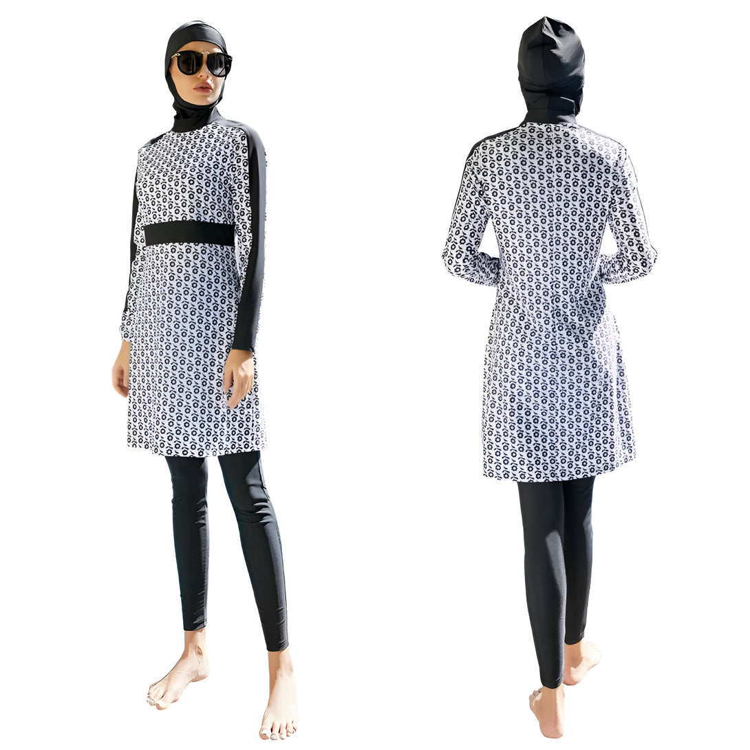 Une femme porte un maillot de bain musulman noir et blanc avec un motif floral. Elle porte également un hijab noir. Le maillot de bain est conçu pour couvrir tout le corps, à l'exception du visage, des mains et des pieds.