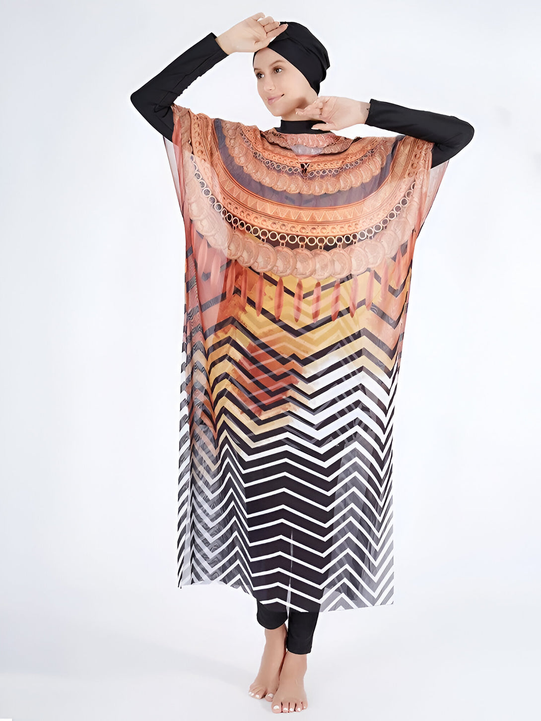 Une femme portant un hijab noir et une robe de plage musulmane à manches longues avec un motif géométrique orange, noir et blanc.