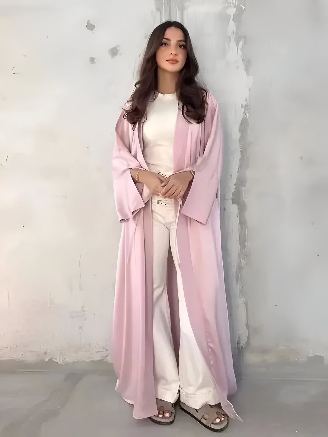 Une femme élégante porte une longue robe rose en satin, parfaite pour une occasion spéciale. Découvrez notre collection de vêtements musulmans pour femmes.