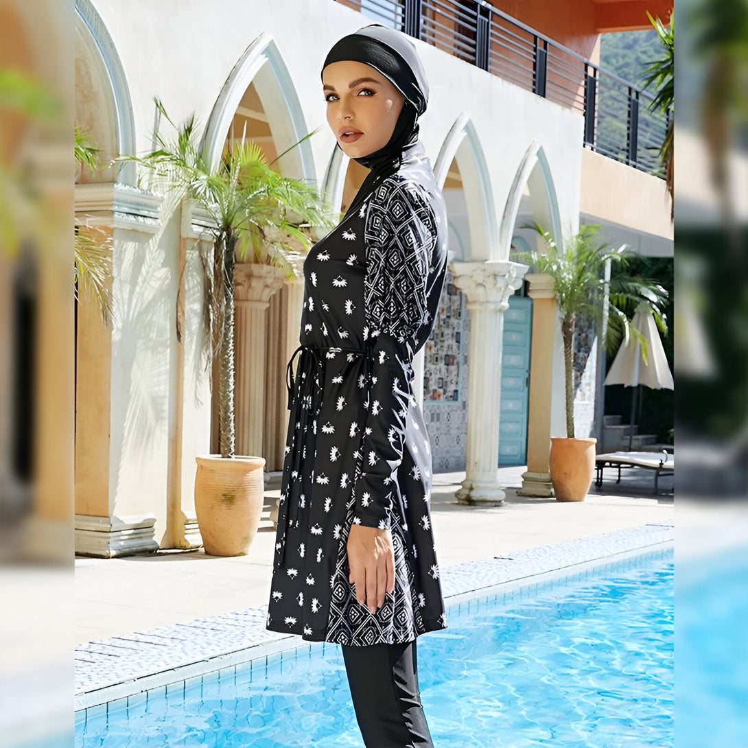 Une femme portant un maillot de bain musulman noir et blanc avec un motif floral près d'une piscine.