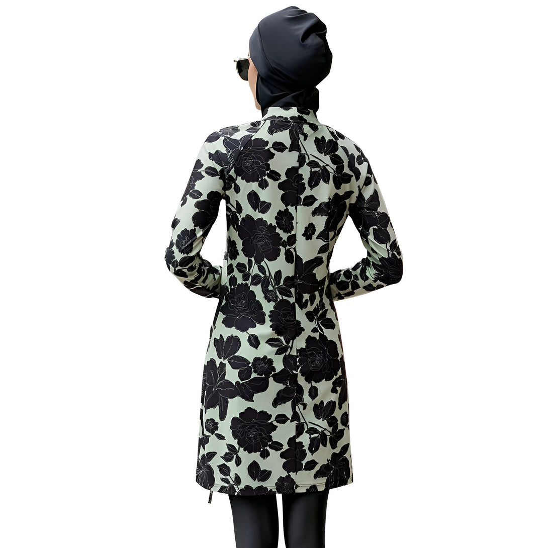 Une femme portant un maillot de bain musulman vert avec un motif floral noir, vu de dos.