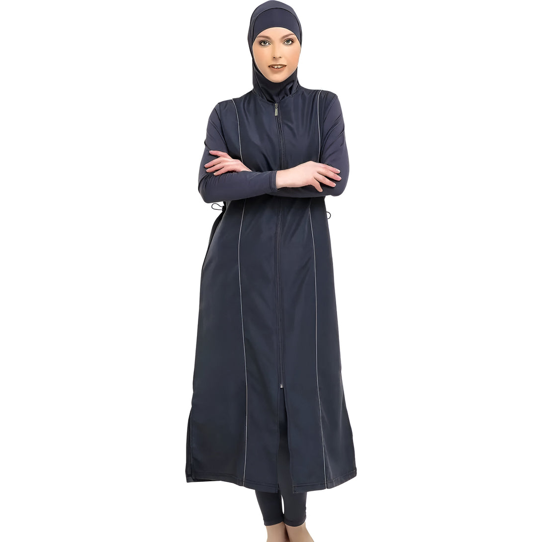 Une femme portant un maillot de bain musulman bleu foncé avec une fermeture éclair sur le devant et des détails blancs.