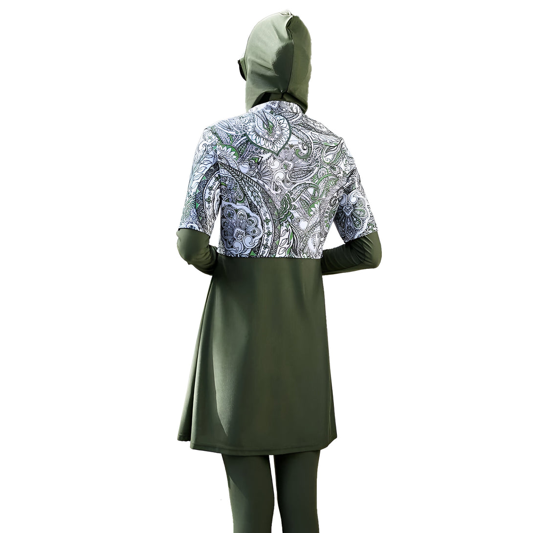 Une femme porte un maillot de bain musulman vert avec un motif paisley blanc et vert. Le maillot de bain est à manches longues et a une jupe.