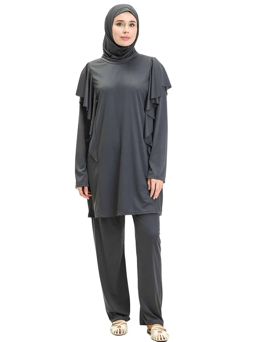 Une femme portant un ensemble de vêtements de bain islamiques gris, avec un hijab assorti, et des sandales blanches.