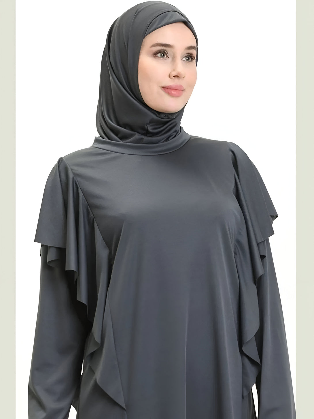 Une femme portant une robe grise à manches longues avec des volants sur les épaules et un hijab assorti.  Vêtements musulmans pour femmes.