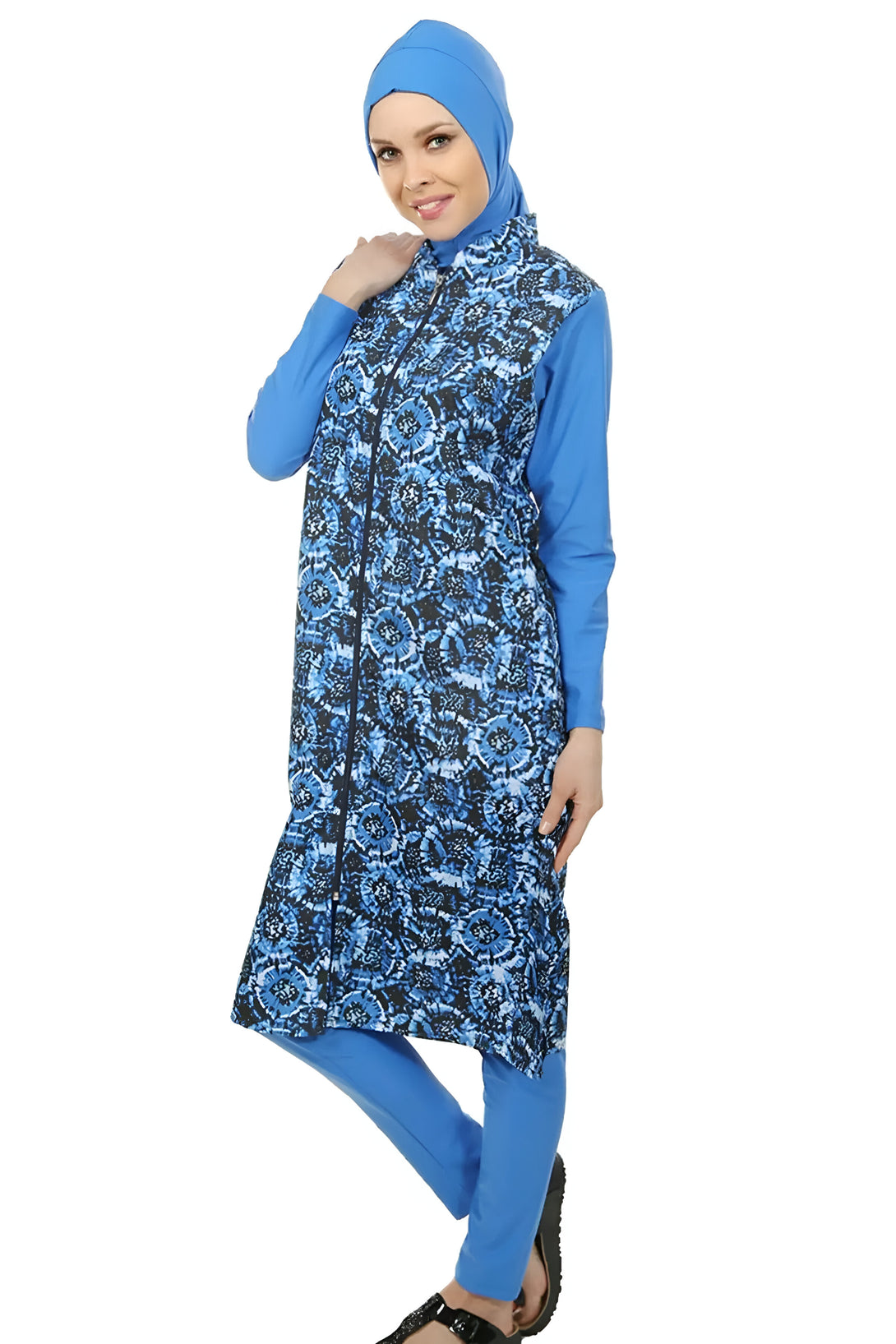 Une femme portant un maillot de bain musulman bleu avec un motif floral. Le maillot de bain comprend une longue tunique à manches longues et un pantalon long.