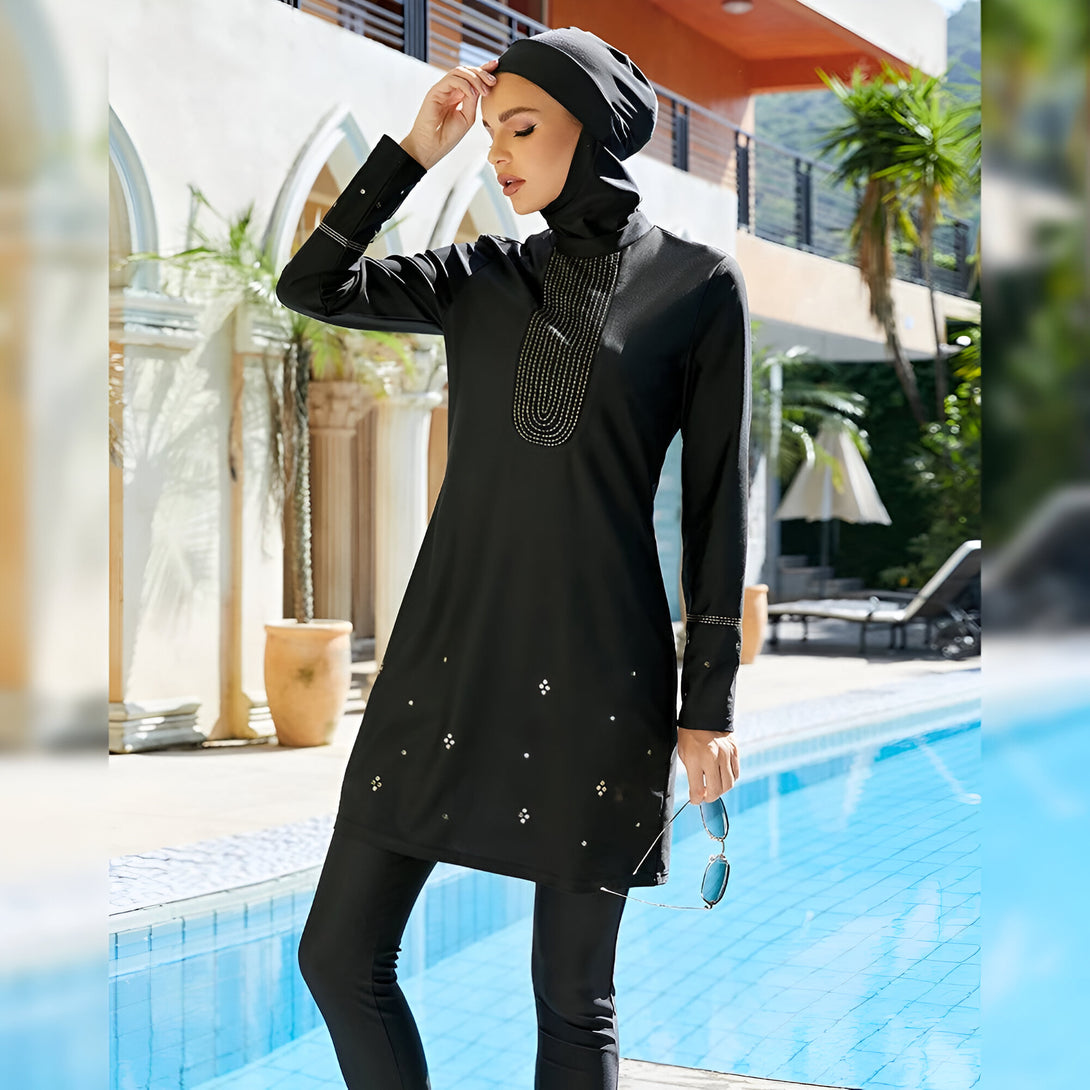 Une femme portant un maillot de bain musulman noir avec des détails dorés près d'une piscine.
