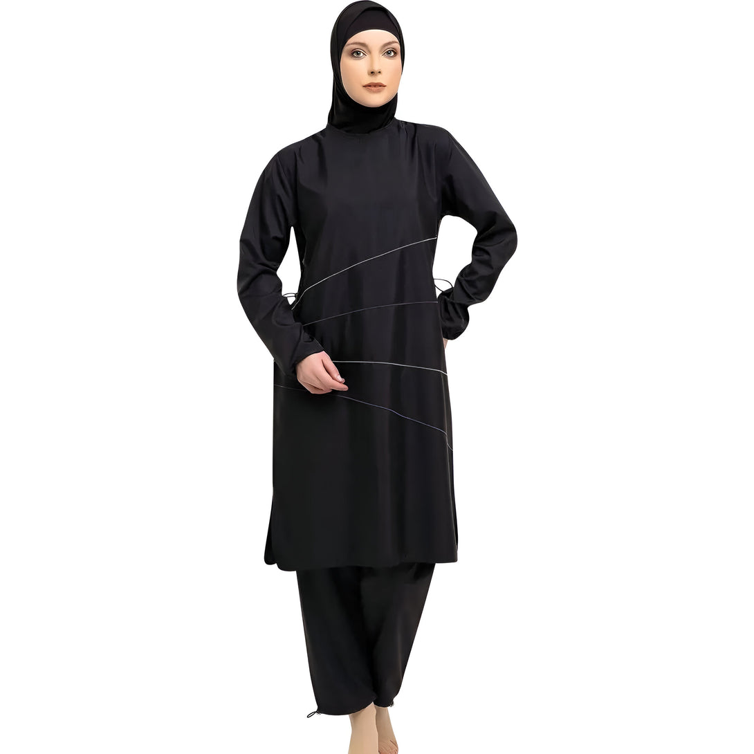 Une femme porte un maillot de bain musulman noir à manches longues avec un hijab assorti. Le maillot de bain a des lignes subtiles de couleur argentée et violette.