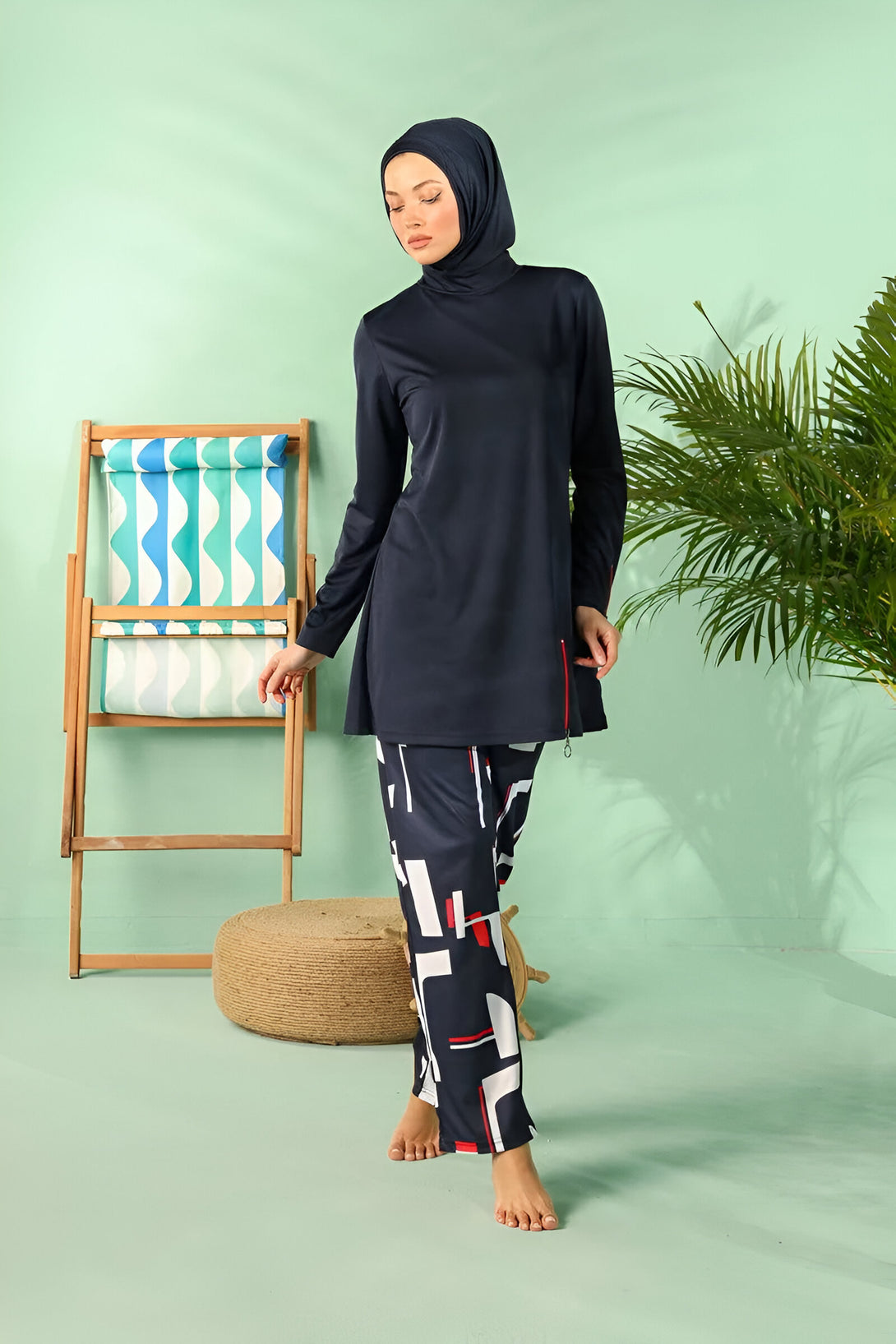 Une femme portant un hijab et un maillot de bain musulman bleu marine avec un pantalon imprimé.