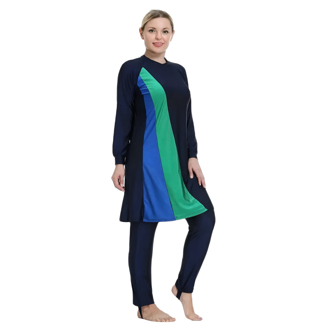 Une femme portant un maillot de bain musulman bleu marine, bleu et vert. Le maillot de bain a des manches longues et des pantalons longs.